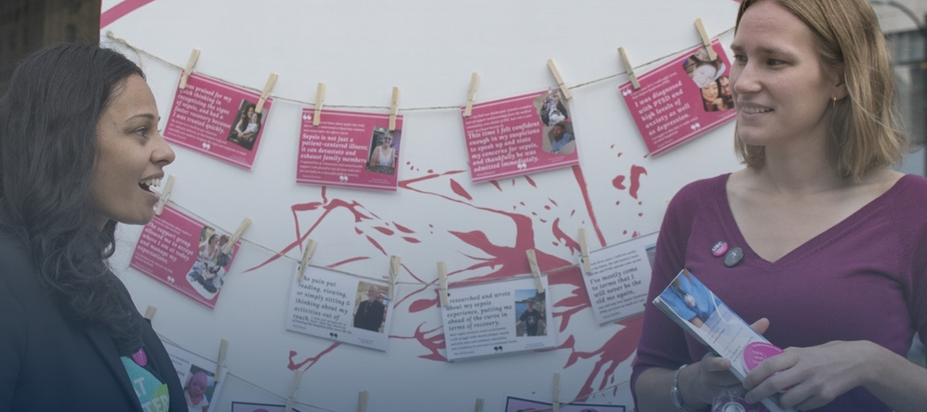 Two women talking in front of display poster 