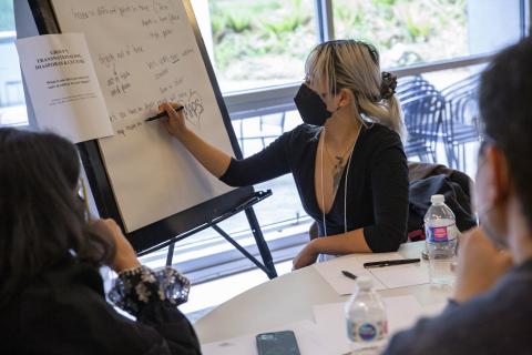 A woman writing on a chart with two people at her table watching her