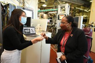 a person wearing a mask and holding something in their hand, showing it to another person